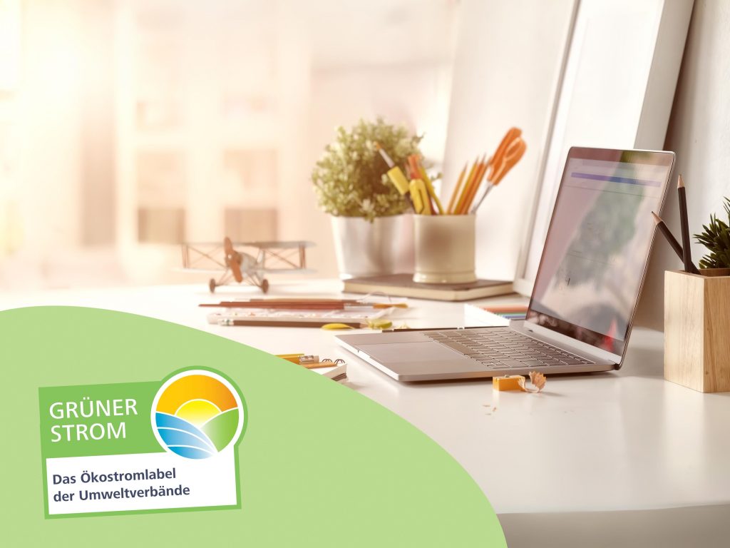 Ein Foto eines aufgeklappten Laptops in einem sonnendurchfluteten Zimmer mit dem Logo des Grüner Strom Label e.V.